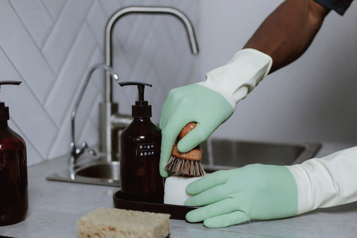 A woman in a red uniform cleans indoors with a blue bucket, ensuring a spotless environment.